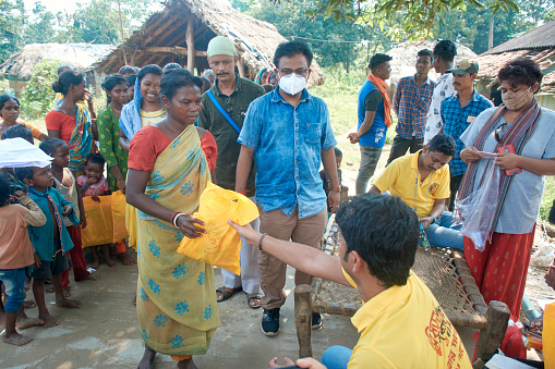 Purulia, West Bengal, 10-03-2021: Members of charitable organisation donating clothes to poor Kheria Sabar (or Shabar) tribal villagers, in midst of pandemic.\n\nSabar tribes are indigenous community people, one of the Adivasi of Munda ethnic group tribe who live mainly in Odisha and West Bengal. Photo taken in a remote village near Bandwan, where most peoples are extremely poor and largely deprived of basic amenities and economic development.