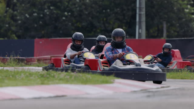 Latin American group of friends having fun at a track of go-carts