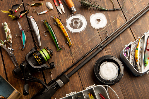 Various fishing accessories, silicone jig and metal spoon, and on wooden background
