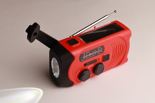 Small red portable radio rechargeable with solar panels or manually with a crank. Flashlight included