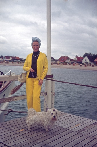 Northern Germany (exact location unknown), 1974. A lady walks her dog on a boardwalk at a marina.