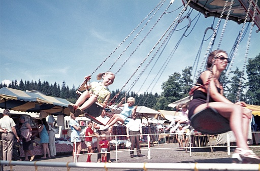 West Germany (exact location unknown), 1976. Mother and daughter are doing a couple of laps on the chain carousel at a fairground.