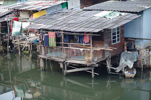 Old damaged thai stilt slum homes at canal in Bangkok Ladprao