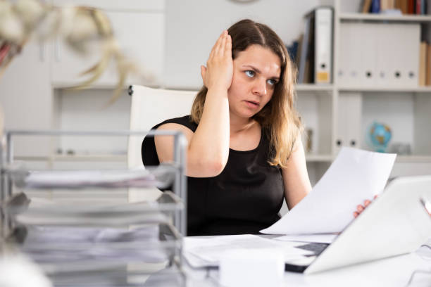 istock Upset woman working with laptop and papers at office 1397951709