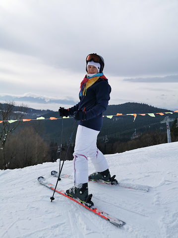 A woman is skiing on a slope against the backdrop of mountains.