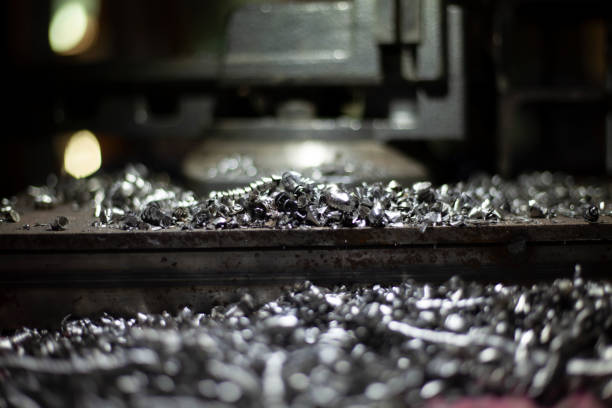 Metal shavings intricately twisted and coiled, resulting from a precision lathe machining process. The metallic spirals display a range of colors under light, highlighting the machining craftsmanship and detail involved in the process.