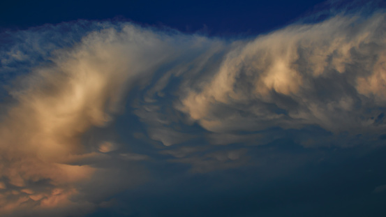 headwinds ruffling a large band of orange-shaded cumulus clouds, floating under a blue sky - POA, SAO PAULO, BRAZIL.