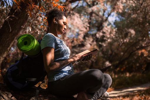 Woman Sitting On Tree Trunk In Forest reading book