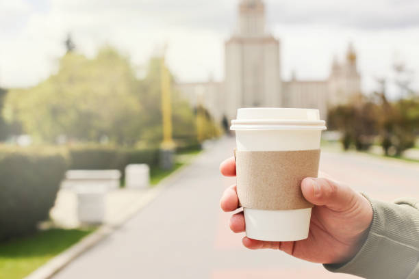 istock Mockup of take away disposable paper coffee container or cup in man's hand on street. copy space. ecology , lifestyle concept. selective focus 1397957607