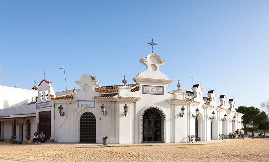 El Rocio, Spain - 10th April 2022. Exterior of La Capilla Votiva Nuestra Senora de Rocio, the Votive Chapel of Our Lady of Rocio in which candles are lit and prayers are said. It is situated in the village of El Rocio, where all the streets are sand rather than tarmac.