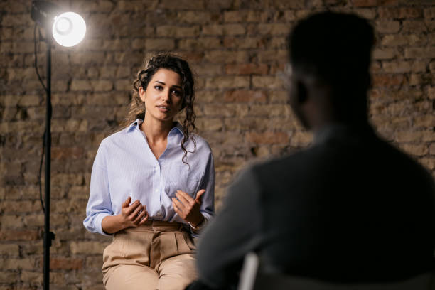 Young woman giving an interview in a studio Attractive woman giving an interview in a studio, gesturing with his hands while she is talking media interview photos stock pictures, royalty-free photos & images