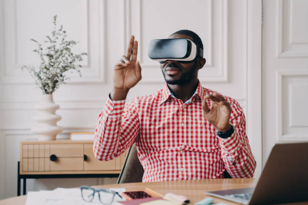 istock Focused Aframerican man in VR glasses enjoying augmented reality while sitting at workplace 1397963493