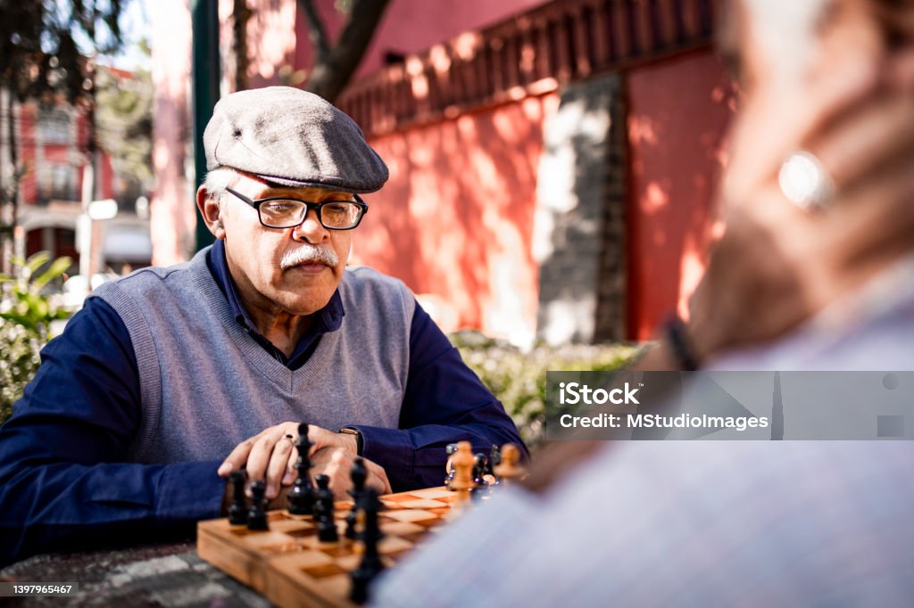 Two senior men playing chess Two senior men playing chess at the park Playful Stock Photo