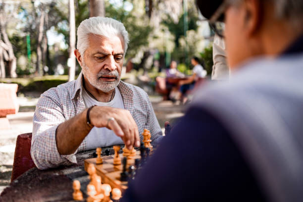 ältere freunde spielt schach - concentration chess playing playful stock-fotos und bilder