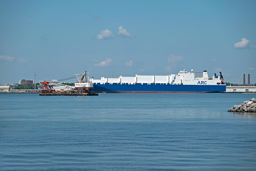 Charleston, SC, USA - May 18, 2022: Atlantic, a 54-meter bucket dredger owned by Norfolk Dredging Company, in Charleston Harbor, with ARC Endurance vehicles carrier in the background.