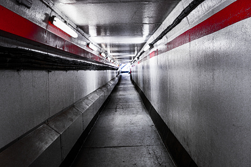 A view down a walkway tunnel with a red and black stripe running horizontally down it