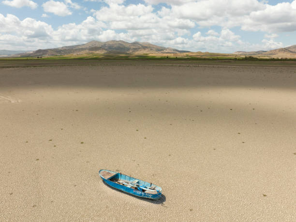 Aerial view of a fishing boat on a drought dry lakebed. Aerial view of a single fishing boat on the dry surface of a drought lake bed. Taken via drone. Burdur,  Turkey. lake bed stock pictures, royalty-free photos & images