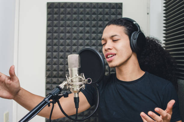 caucasian young man with curlers singing in professional studio stock photo