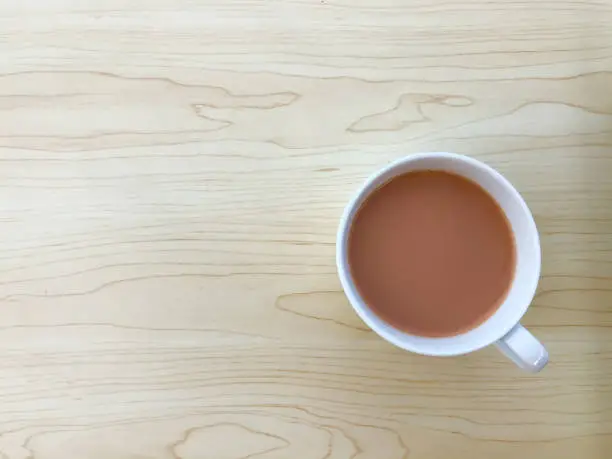 Photo of Top view of hot milk tea or teh tarik in a white cup. Copy space