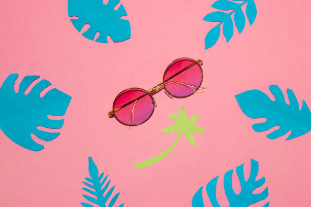 istock sunglasses on a pink background under a paper palm tree around tropical blue leaves, creative summer concept 1397974424