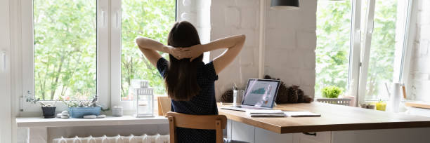 istock Panoramic image woman sit at desk with hands behind head 1397974590