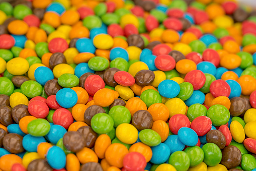 Green, blue, red, orange, brown chocolate candies in store, full frame.