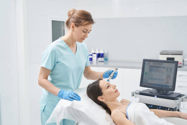 Doctor beautician performing Hydradermabrasian treatment in clinic Female cosmetologist in sterile gloves cleaning woman face with facial cosmetology machine or peeling hydro device sports training clinic stock pictures, royalty-free photos & images