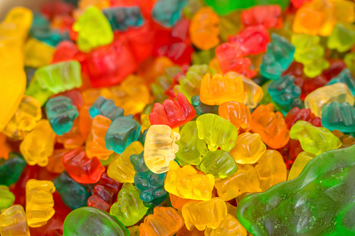 Green, red, orange, yellow jelly candies in store, full frame.