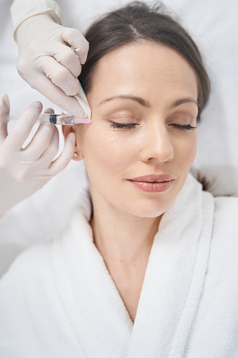 Mujer que recibe una inyección de estiramiento facial en un salón de belleza photo
