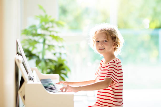 istock Child playing piano. Kids play music. 1397986363