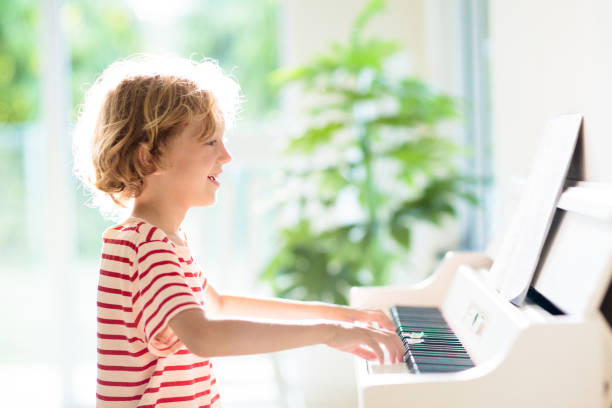 istock Child playing piano. Kids play music. 1397993694