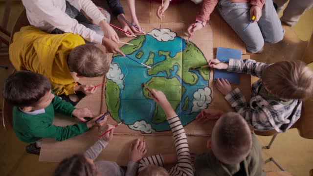 Above view of school children drawing the planet earth