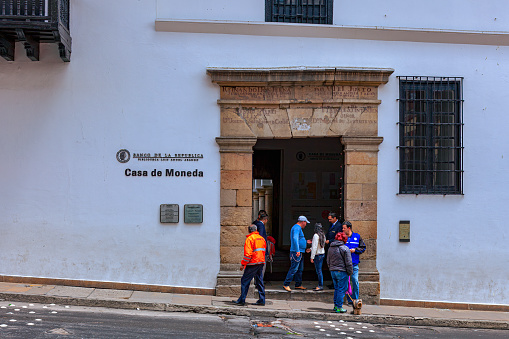 Bogotá, Colombia - July 20, 2016: Looking directly into the entrance to the old Spanish colonial mint. It is today the Museum Casa de Moneda and owned by the Central Bank of the Country. The altitude at street level is 8,660 feet above mean sea level. It is 20th July, National Day and a holiday in Colombia; the street is therefore not as busy as it would normally be. Photo shot on an overcast afternoon; horizontal format. Copy space.