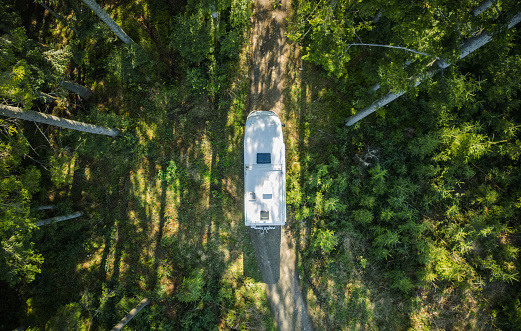 Class C Motorhome Camper Van on a Woodland Country Road Aerial View. Summer Vacation Road Trip.