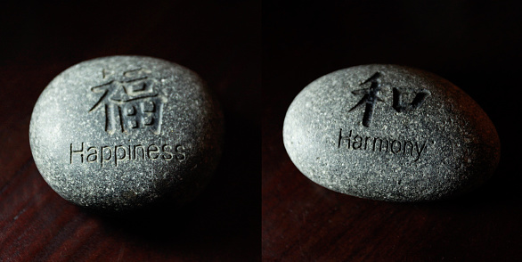Letter happiness and harmony carved on stones isolated on black.