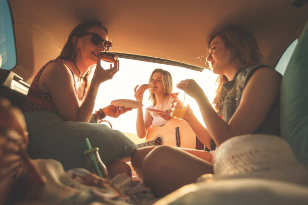 istock Female friends having fun in the car trunk while making a road trip 1398006529