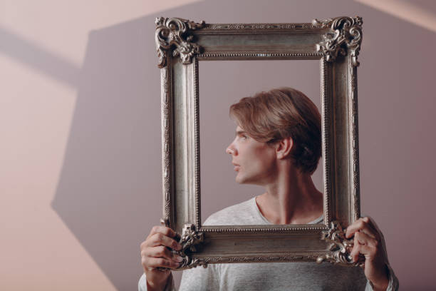 istock Portrait young man standing with picture frame at studio. 1398007119