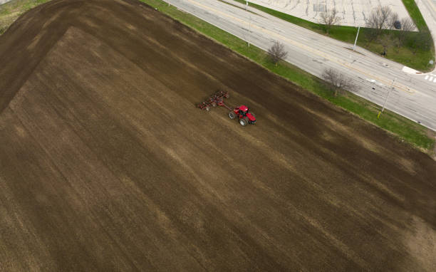 An aerial view above a field as a large, red tractor is seen sowing. stock photo