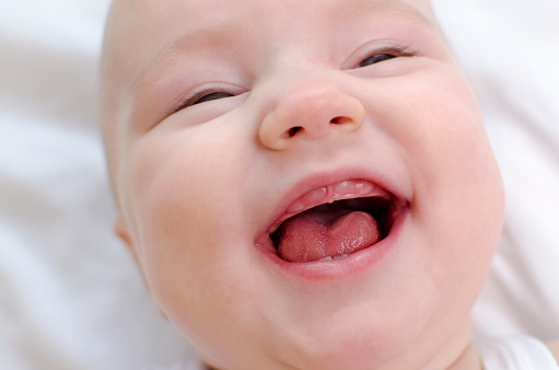 Smiling baby mouth close-up. Infant primary teeth. Children healthcare and soothing concept.