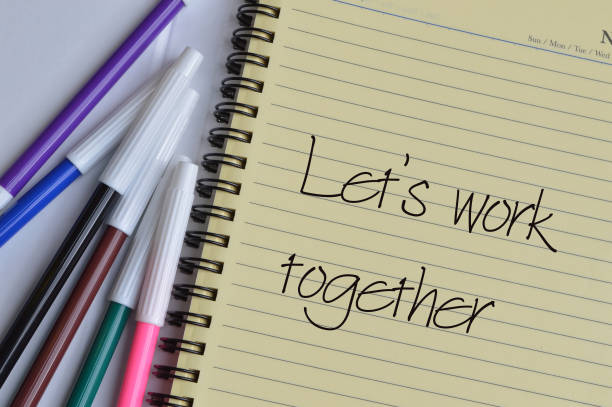 istock Top view of pen colors and notebook written with text LET'S WORK TOGETHER. 1398015697