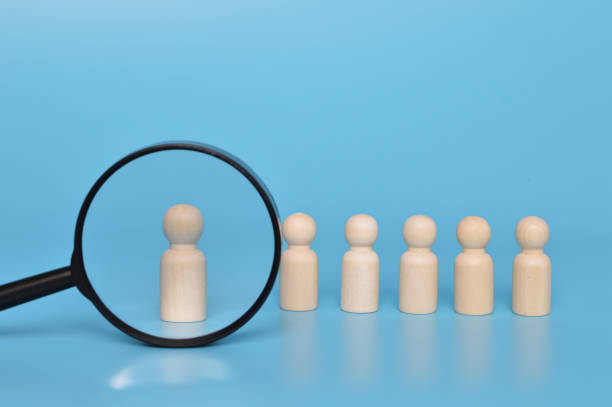 istock Talent sourcing concept. Wooden doll figures and magnifying glass. 1398016871