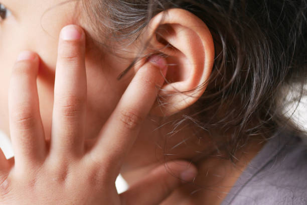 child girl having ear pain touching his painful ear , - young ears imagens e fotografias de stock