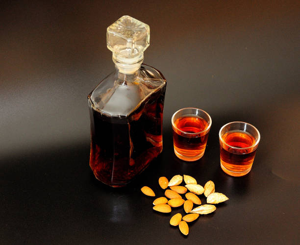 italian almond liqueur, strong homemade alcohol and a scattering of nuts on a black background. - whisky liqueur glass alcohol bottle imagens e fotografias de stock