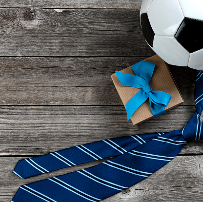 Fathers Day holiday concept with knotted tie, soccer ball and gift box in close up view