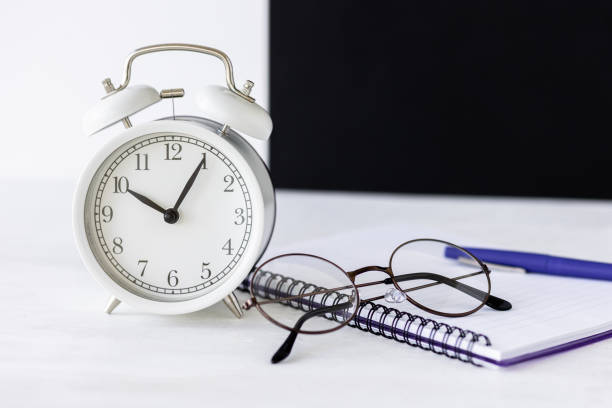 Time to return back to school.  Office stationery. Black board on background. White alarm clock. Copy space for text.