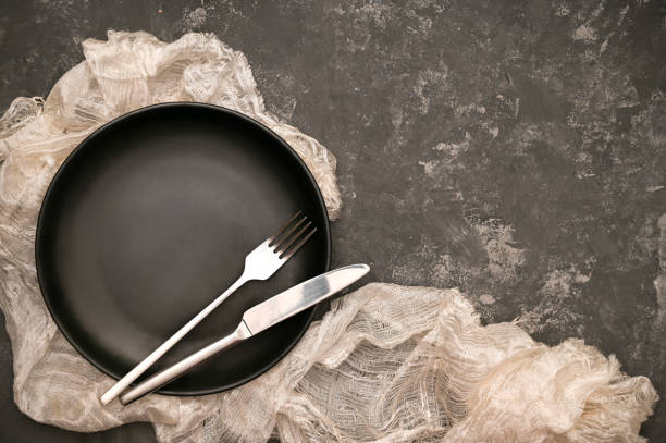 istock Minimal black dining table setting with black ceramic plate and cutlery on dark background. 1398030306