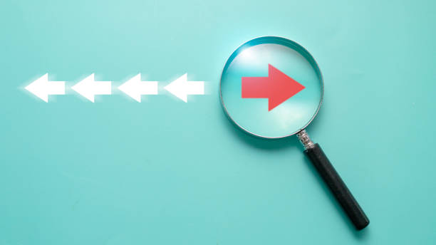 istock Red arrow inside of magnifier glass and different direction from white arrow for focus business disruption and technology transformation concept. 1398033830