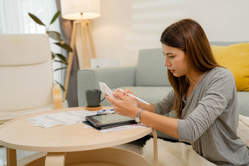 Asian women counting college savings fund, tuition fee for student loan with calculator.