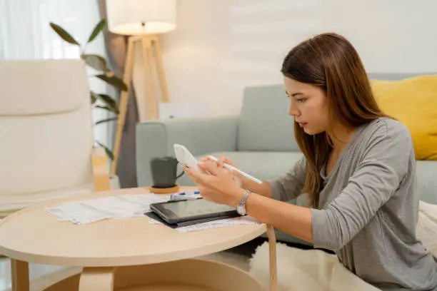 Photo of Woman analyzing documents while sitting at home.