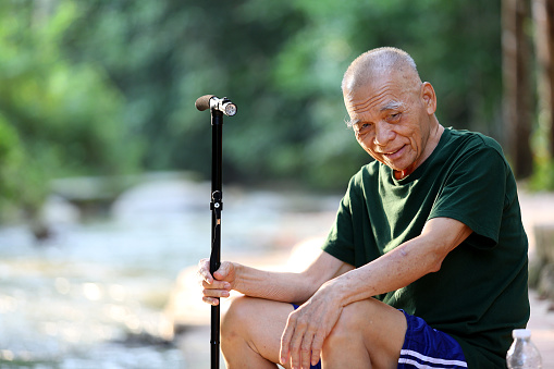 An Asian senior man is  relaxing at nature reserve forest.